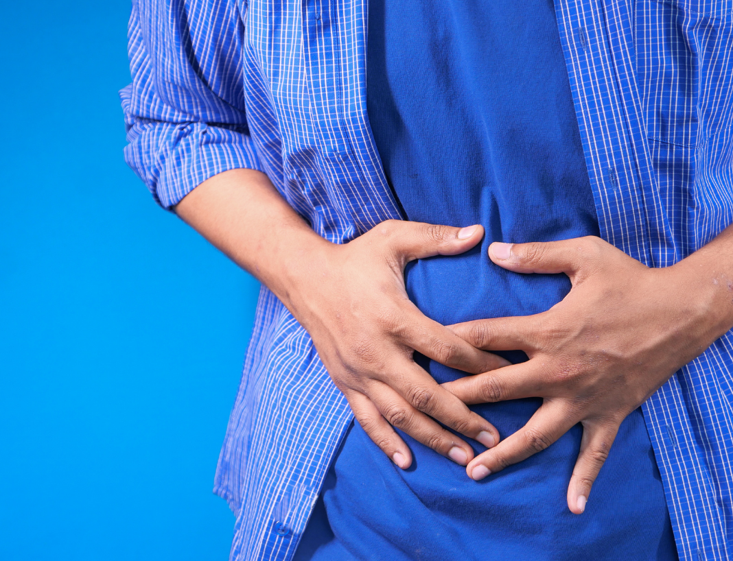 person dressed in blue holding stomach in pain