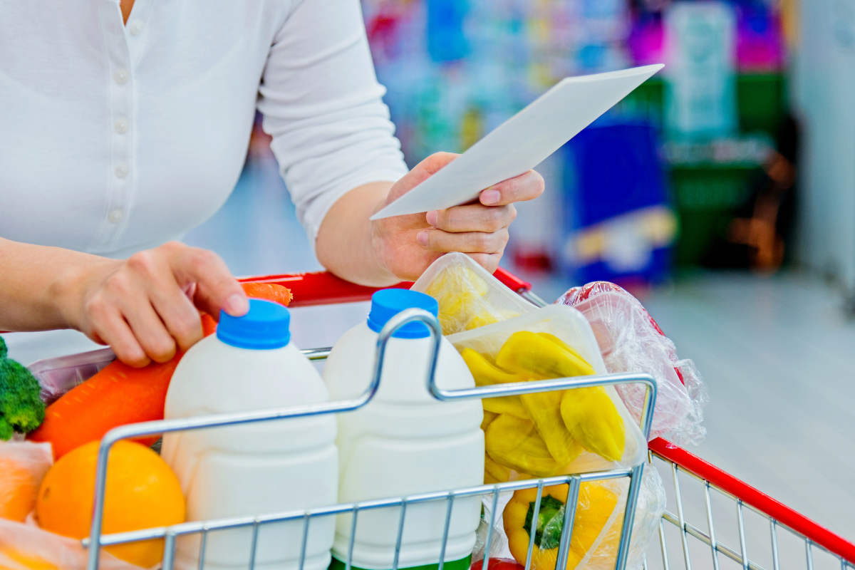 picture of person in store with a trolley and a shopping list